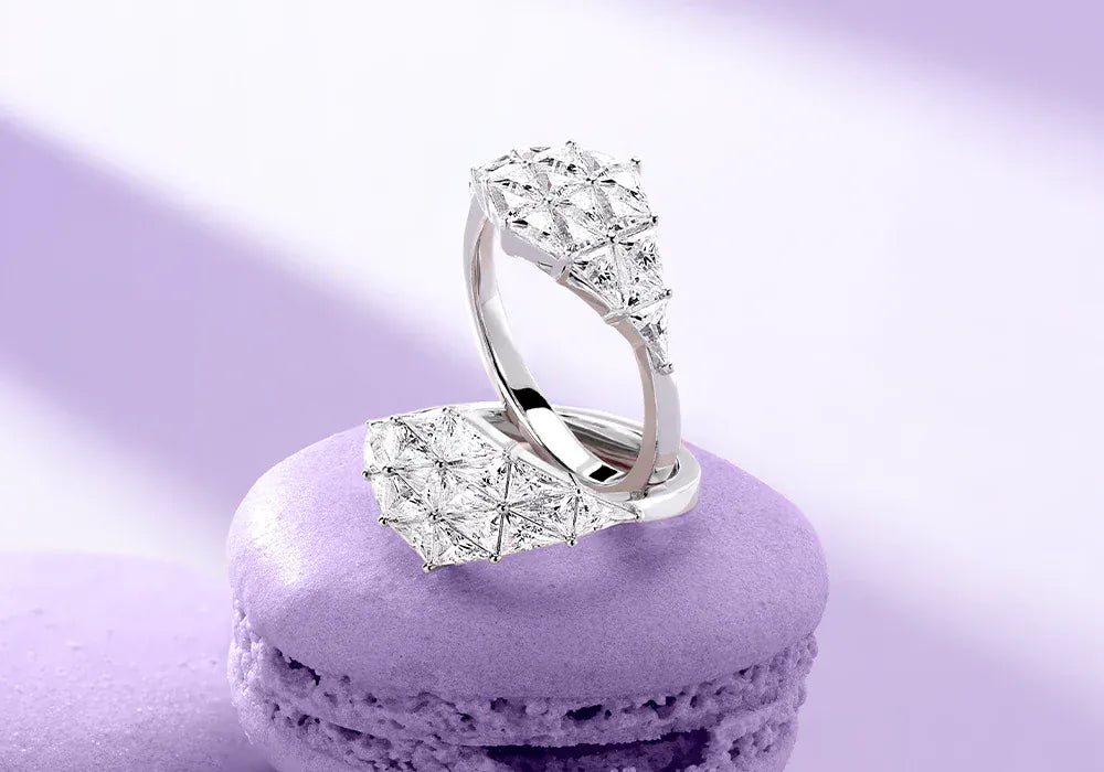 APM MONACO geometric rings with white stones on a purple macaron against a light purple background