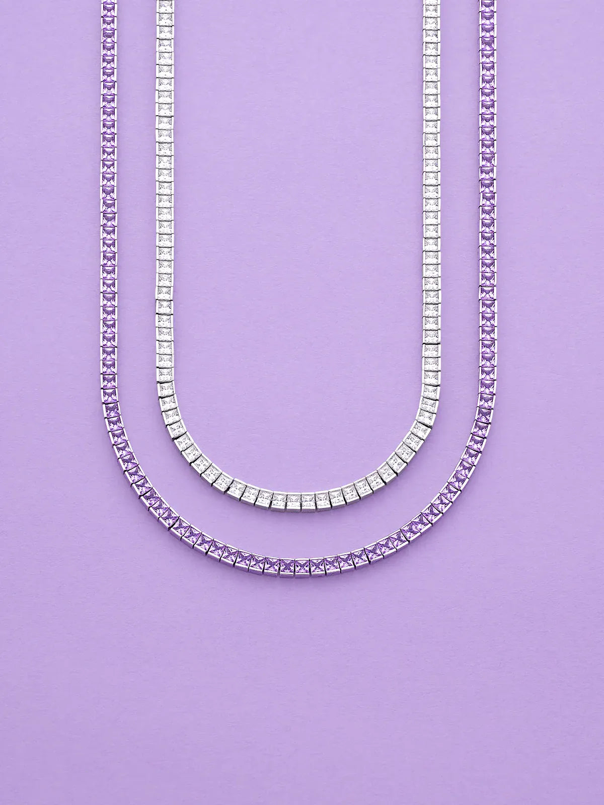 Two APM MONACO Printemps necklaces in silver and purple on a purple background