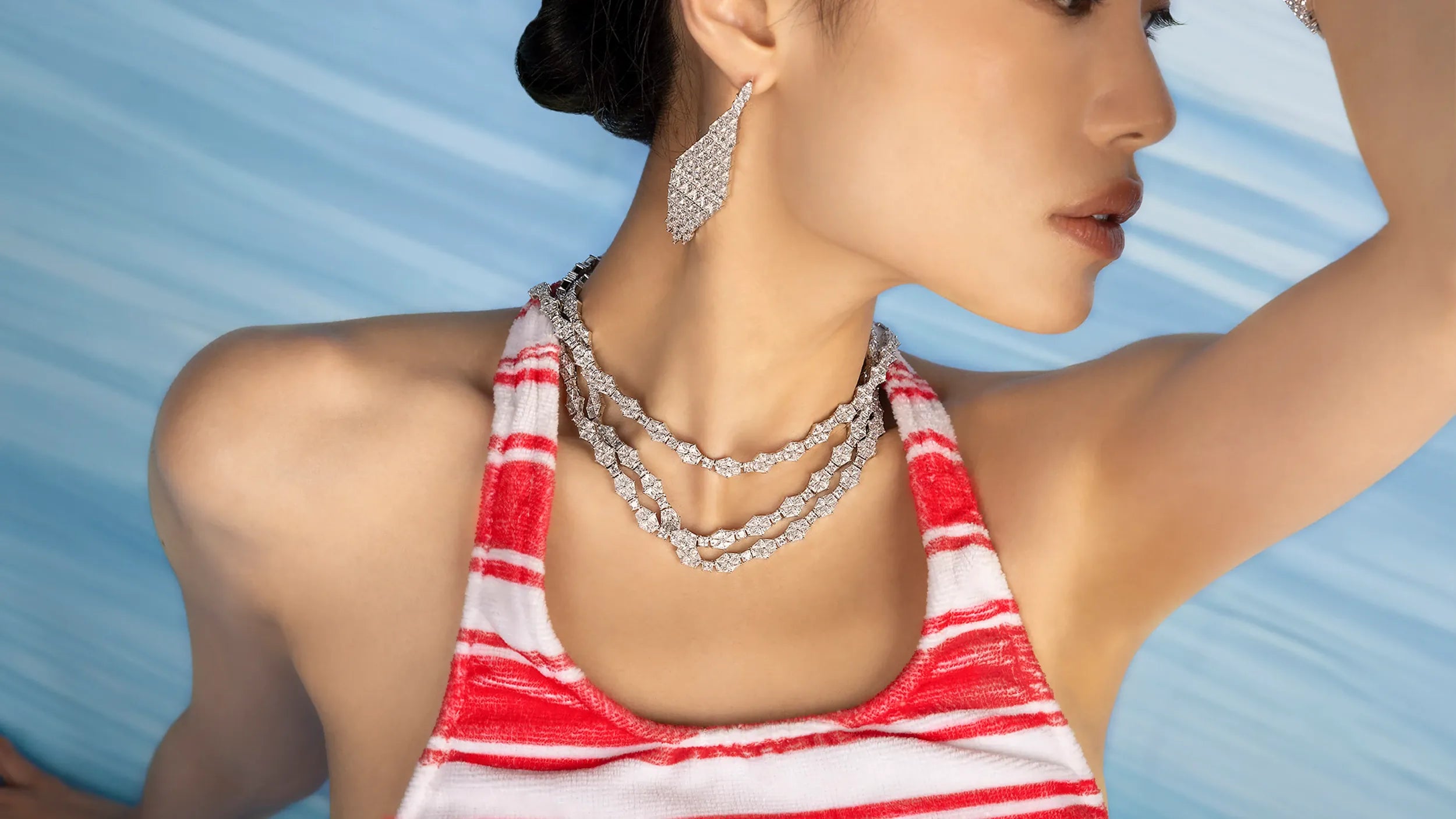 Woman wearing a red and white striped top with APM MONACO white jewelry against a blue background