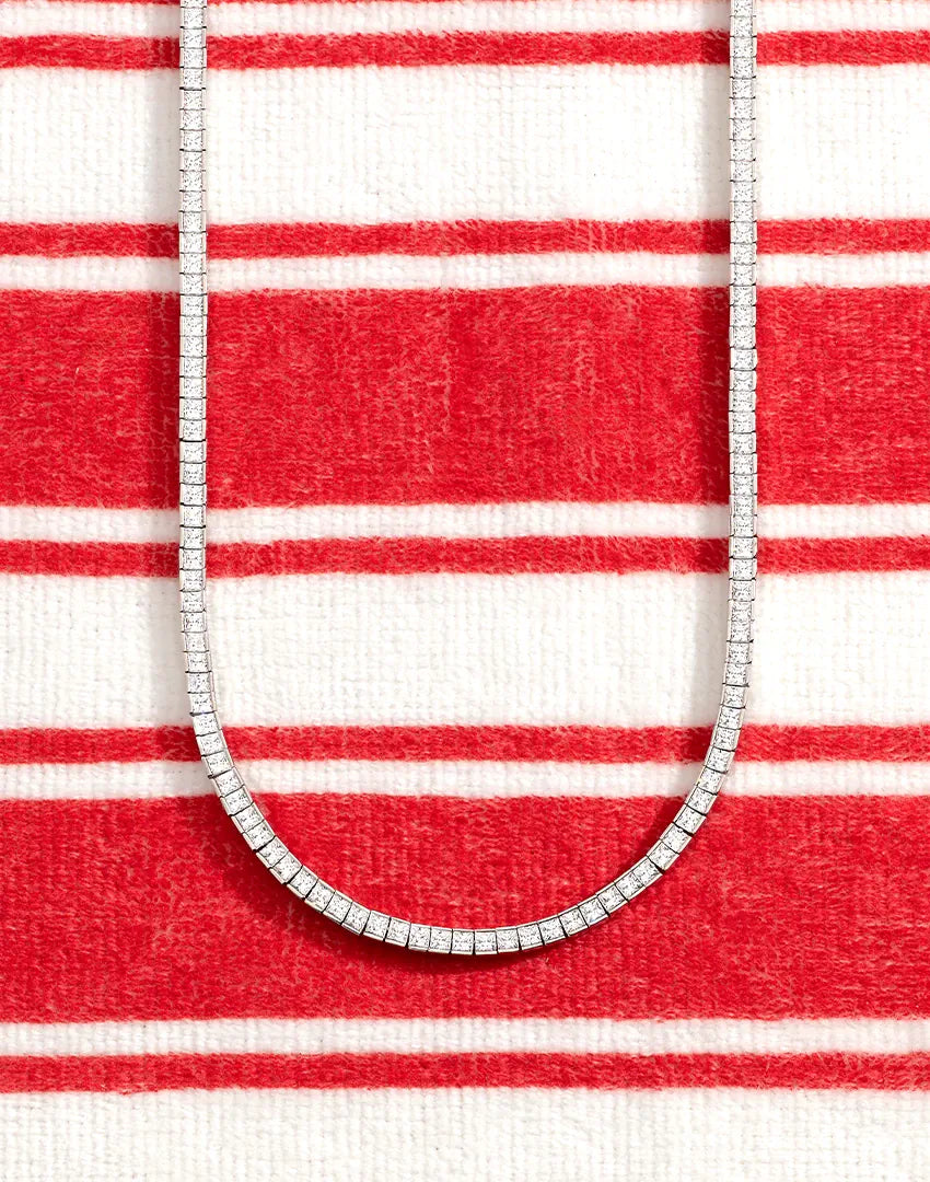 APM MONACO white necklace on a red and white striped fabric background