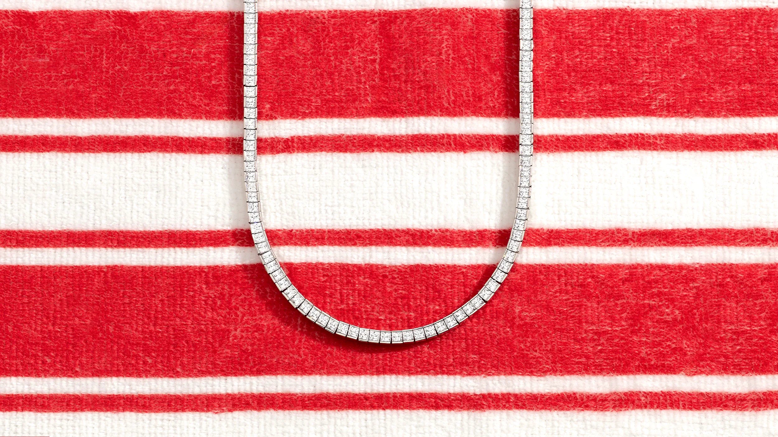 APM MONACO white necklace on a red and white striped fabric background