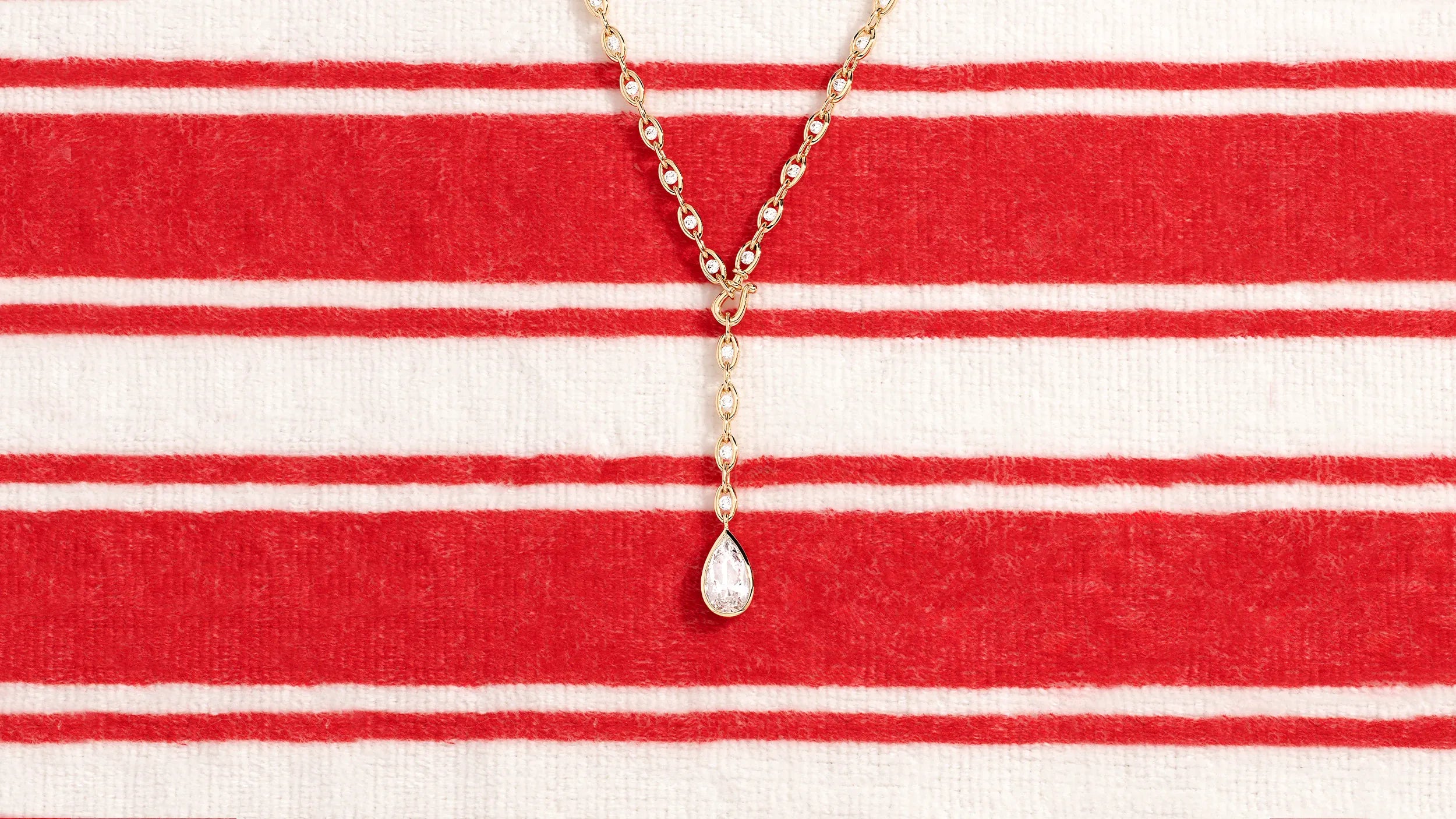 APM MONACO Soleil yellow necklace on a red and white striped fabric background