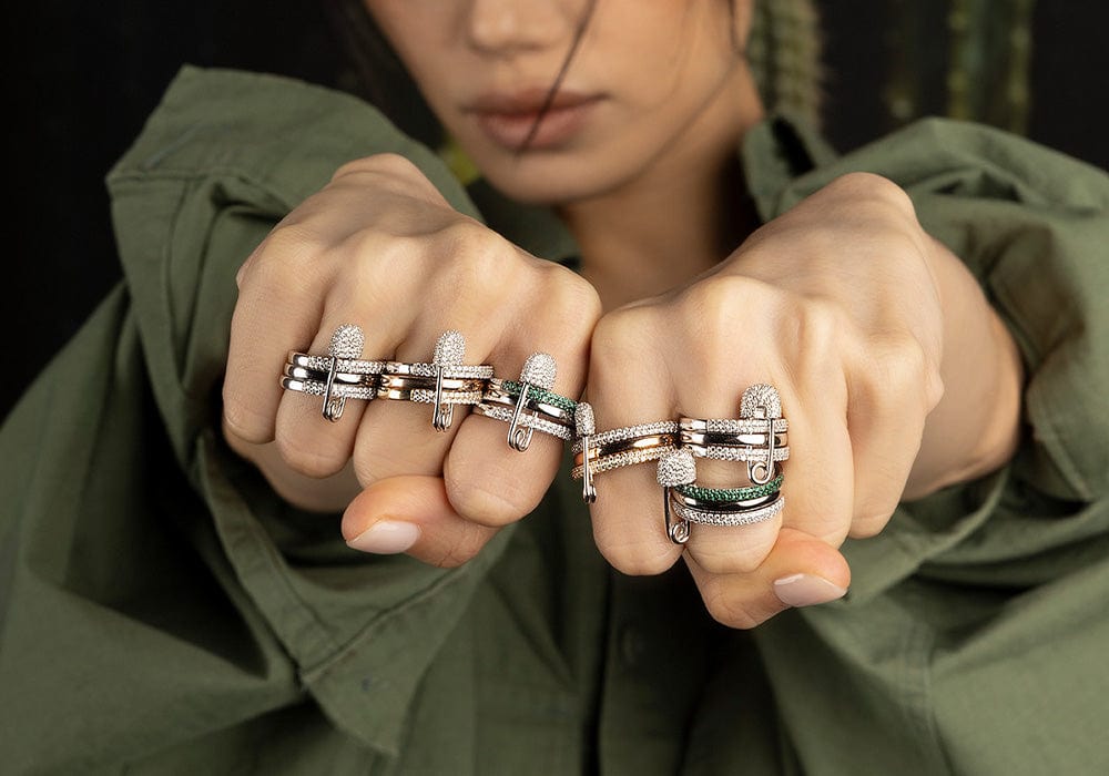 Person wearing multiple silver rings on their fingers against a green dark background