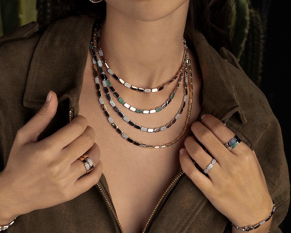 Person wearing multiple yacht club necklaces and rings with a dark background