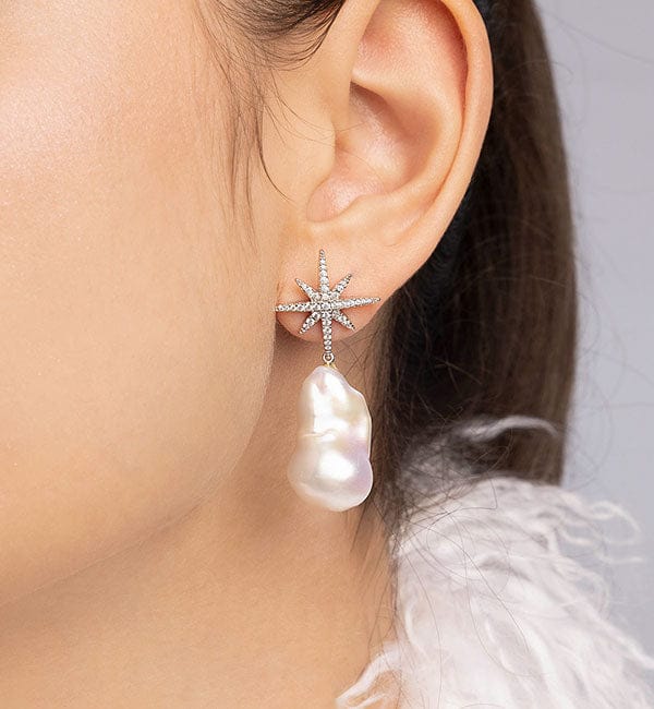 APM MONACO star-shaped earring with a water pearl drop worn by a person