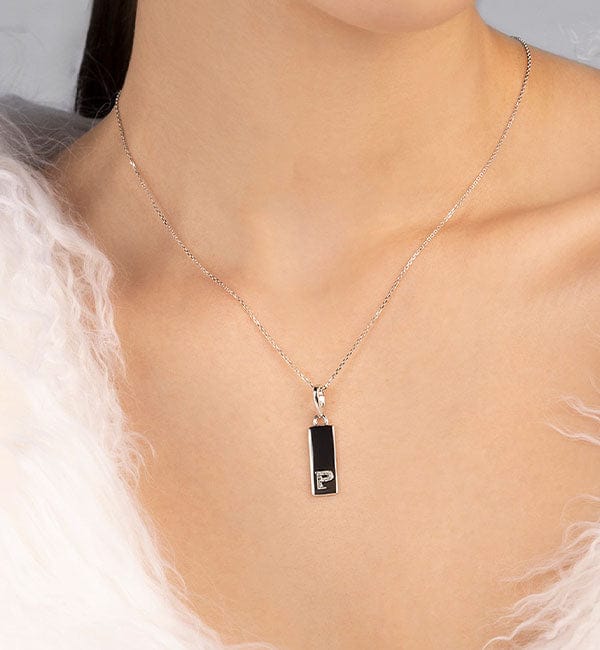 APM MONACO personalized necklace with a pendant featuring a letter 'P' on a person wearing a white fur garment.