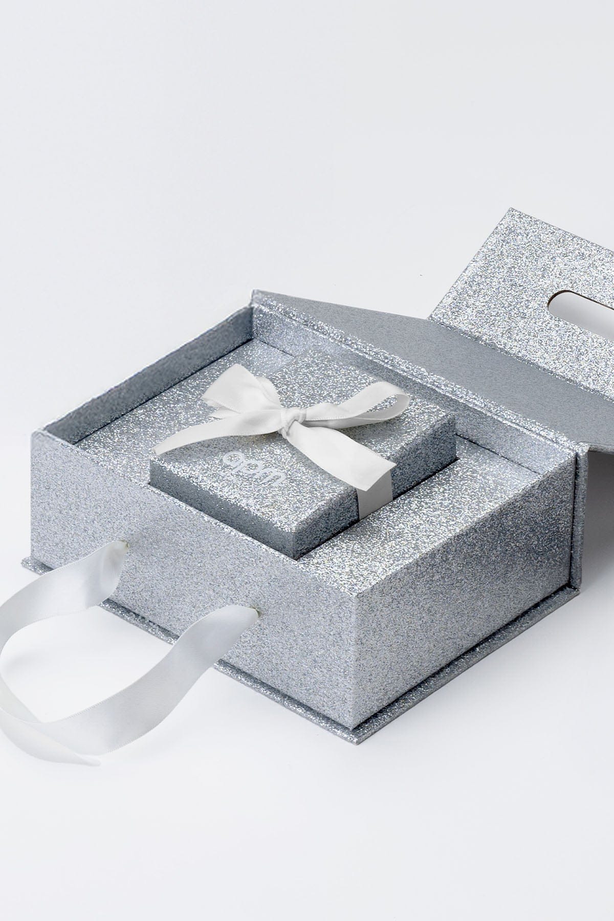 APM Monaco limited edition packaging : Silver jewelry box with a white bow on a white background