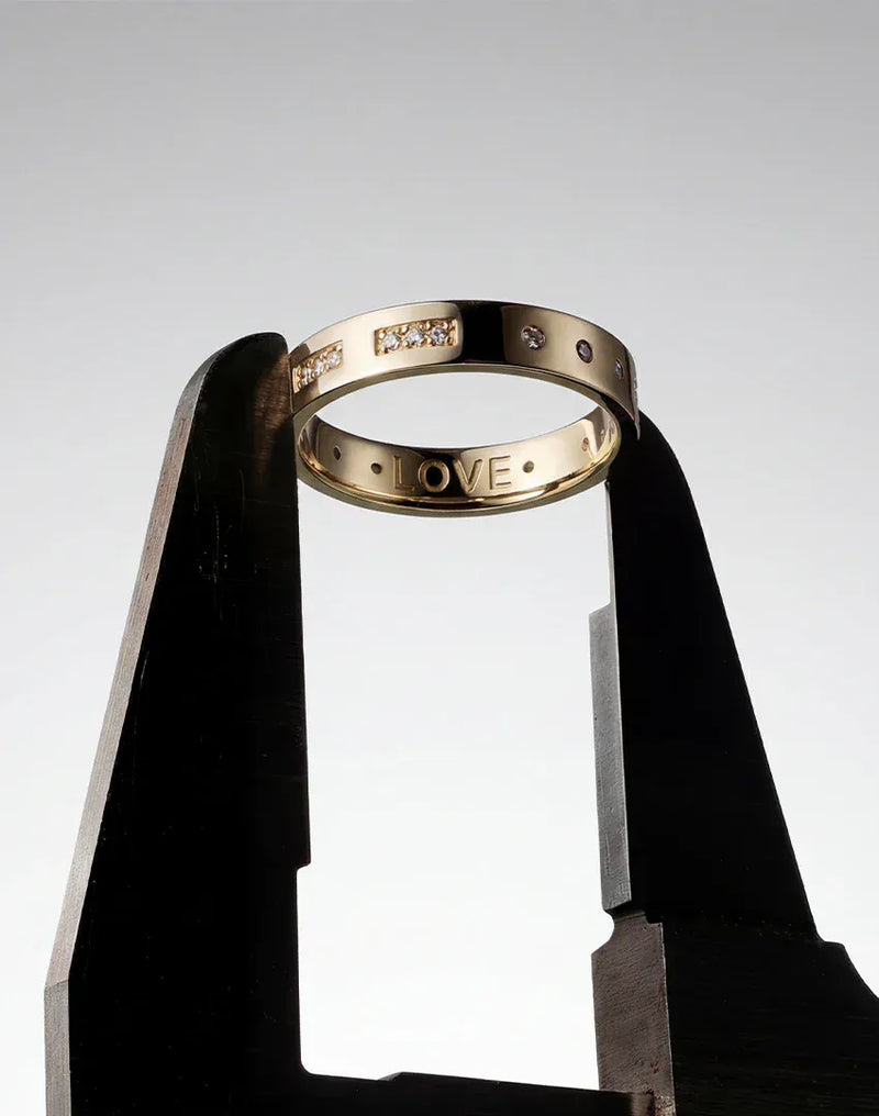 APM Monaco Gold ring with 'LOVE' engraving on a gray background