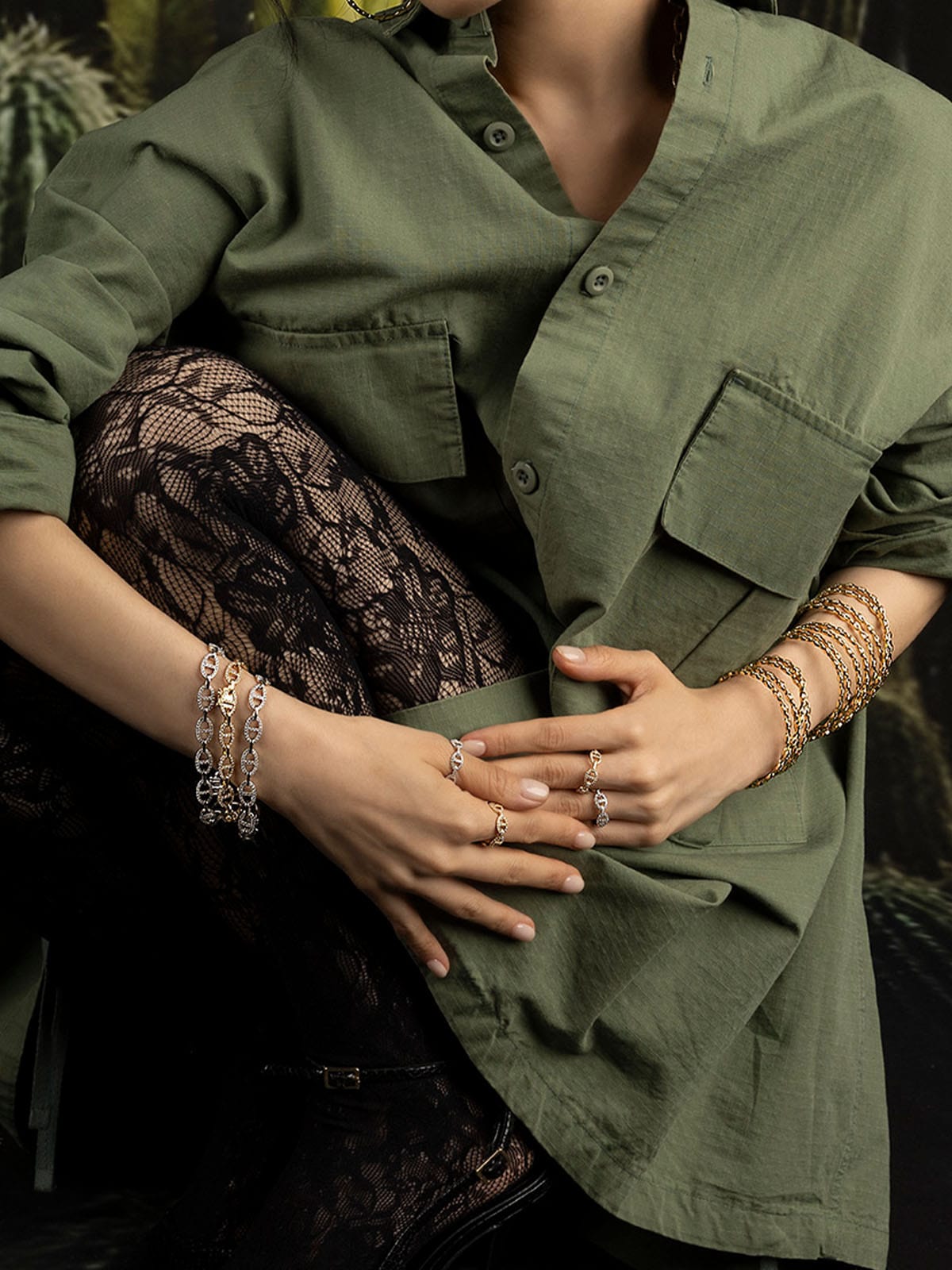 Person wearing a green shirt with lace pants and multiple apm monaco bracelets.