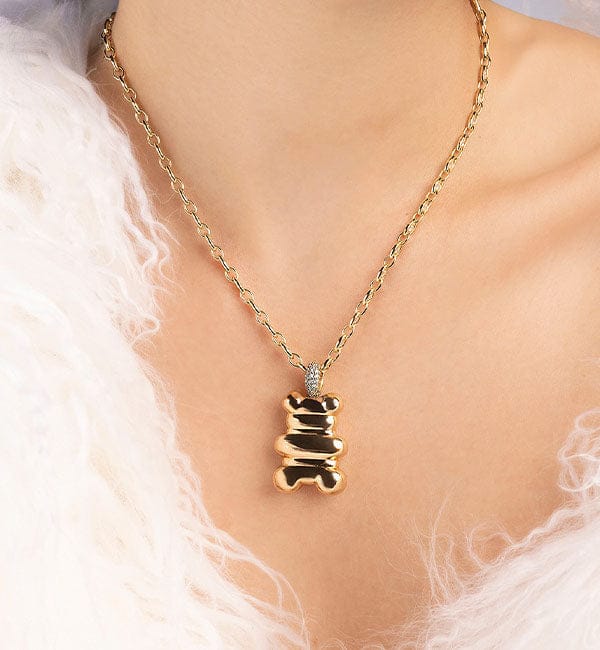 APM MONACO yellow gold bear-shaped pendant necklace on a person wearing a white fur garment.