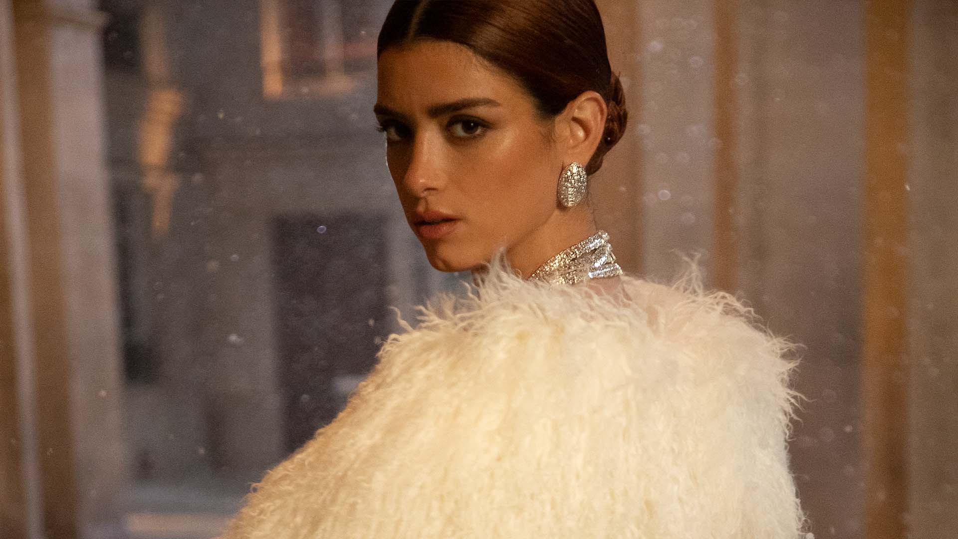 Woman wearing a white feathered outfit with APM MONACO ice jewelry set