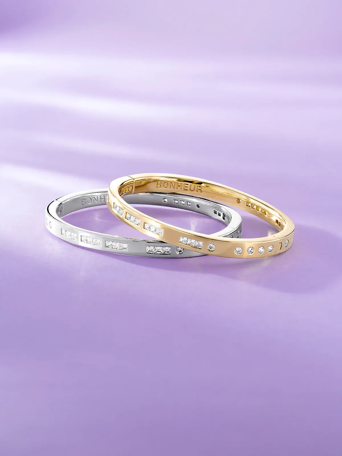 APM Monaco Morse Code bracelets in gold and silver on a purple background