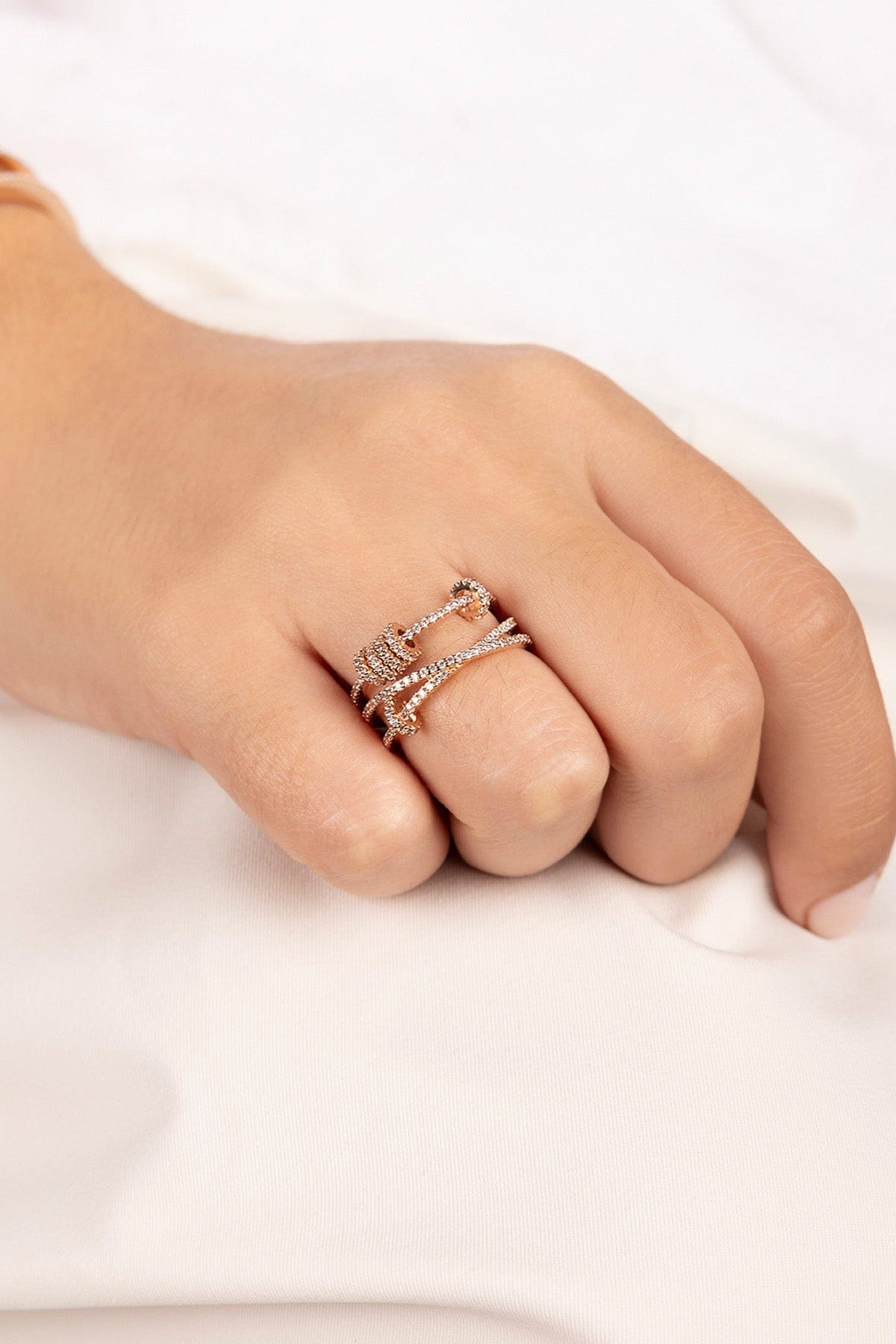 Hand wearing APM MONACO triple ring with sliding-hoops design on white blurred background