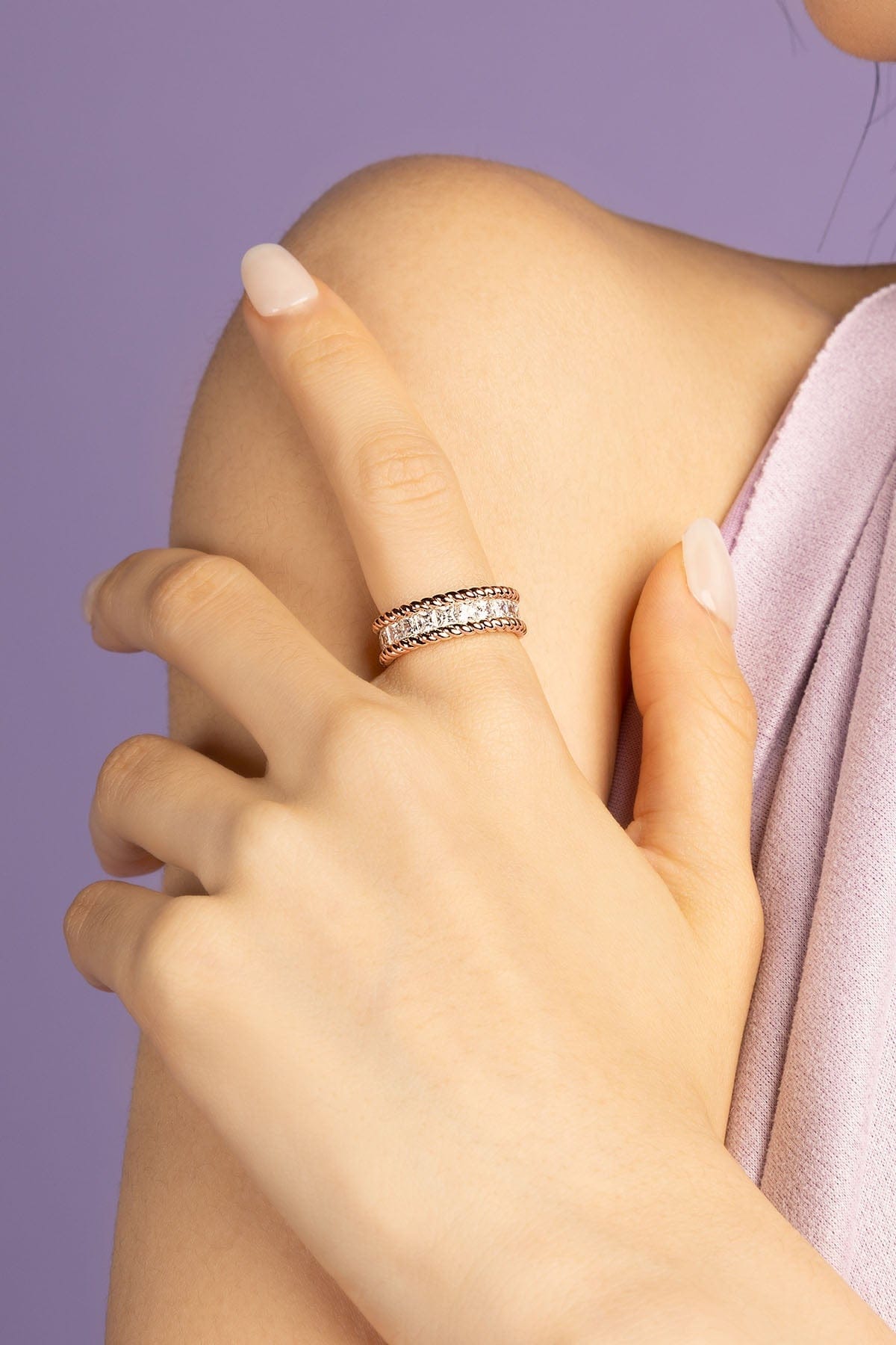 Close-up of a hand wearing a zirconia stones ring on a purple background