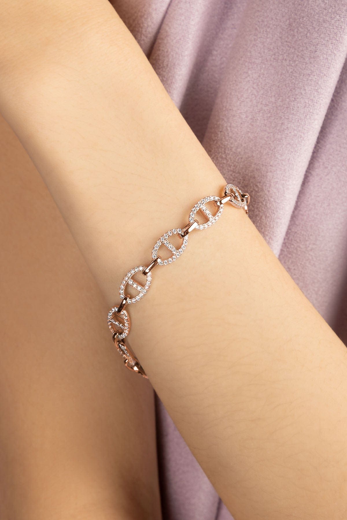 Rose gold bracelet on a wrist against a dark background