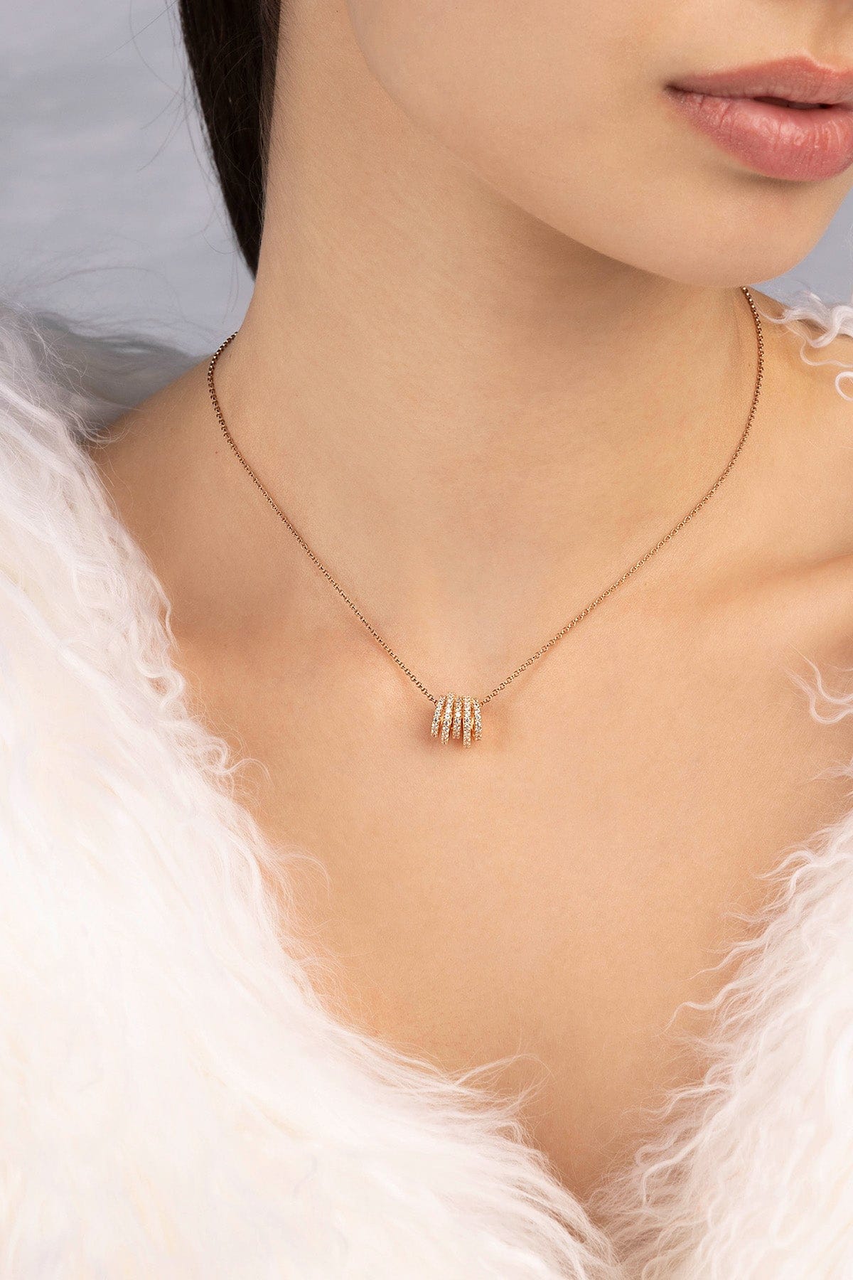 APM MONACO adjustable necklace with hoop design in rose gold on a person wearing a white fur garment
