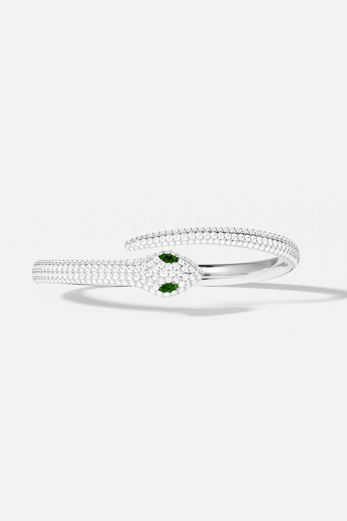 Silver bangle with green gemstones on a white background
