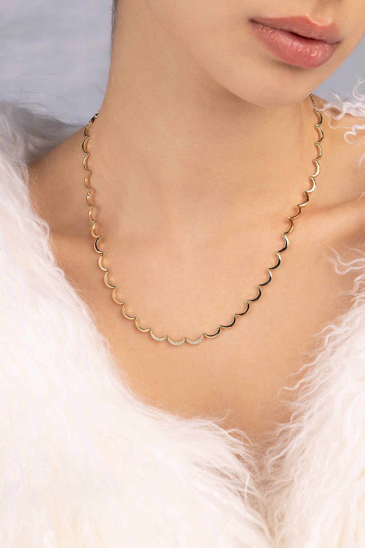 Gold necklace worn by a person with a soft focus background